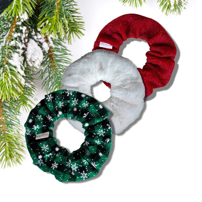 "3-pack holiday scrunchies: cotton green with snowflakes, white faux fur, and sparkly red, featuring hidden zipper pockets for valuables (cash, keys, AirPods) and strong elastic for secure hold. Inspired by the Christmas and winter season, perfect for workouts, festivals, and holiday events.