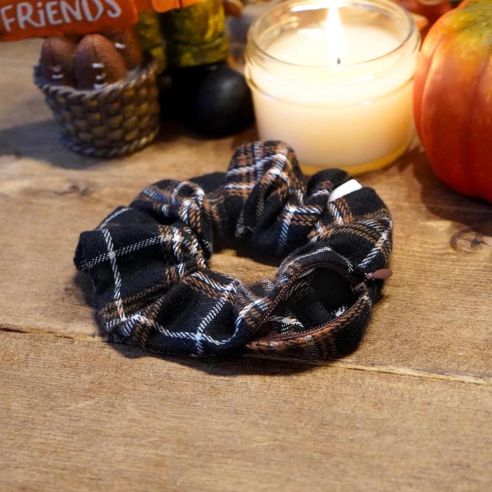 Brown and cream plaid flannel scrunchie with hidden zipper pocket for valuables (cash, keys, AirPods), featuring strong elastic for a secure hold, inspired by Halloween and the fall season, perfect for workouts and festivals.
