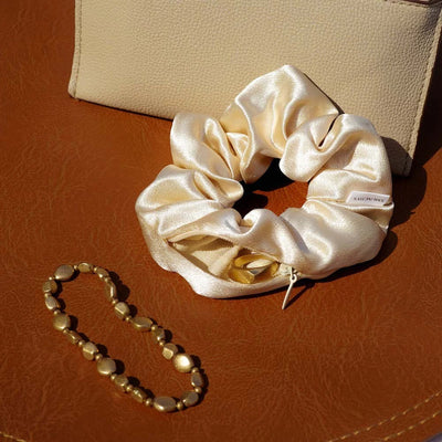 Satin gold hair scrunchie ponytail holder featuring a hidden zipper pocket for storing valuables (cash, keys, AirPods) and strong elastic for a secure hold. Ideal for workouts, festivals, gifts, and holiday stocking stuffers.