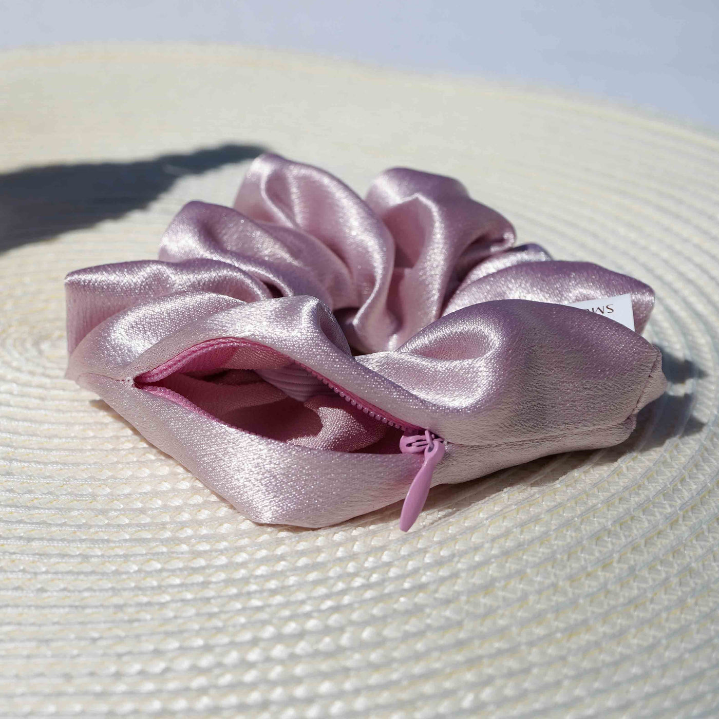 Satin light pink hair scrunchie ponytail holder featuring a hidden zipper pocket for storing valuables (cash, keys, AirPods) and strong elastic for a secure hold. Ideal for workouts, festivals, gifts, and holiday stocking stuffers.