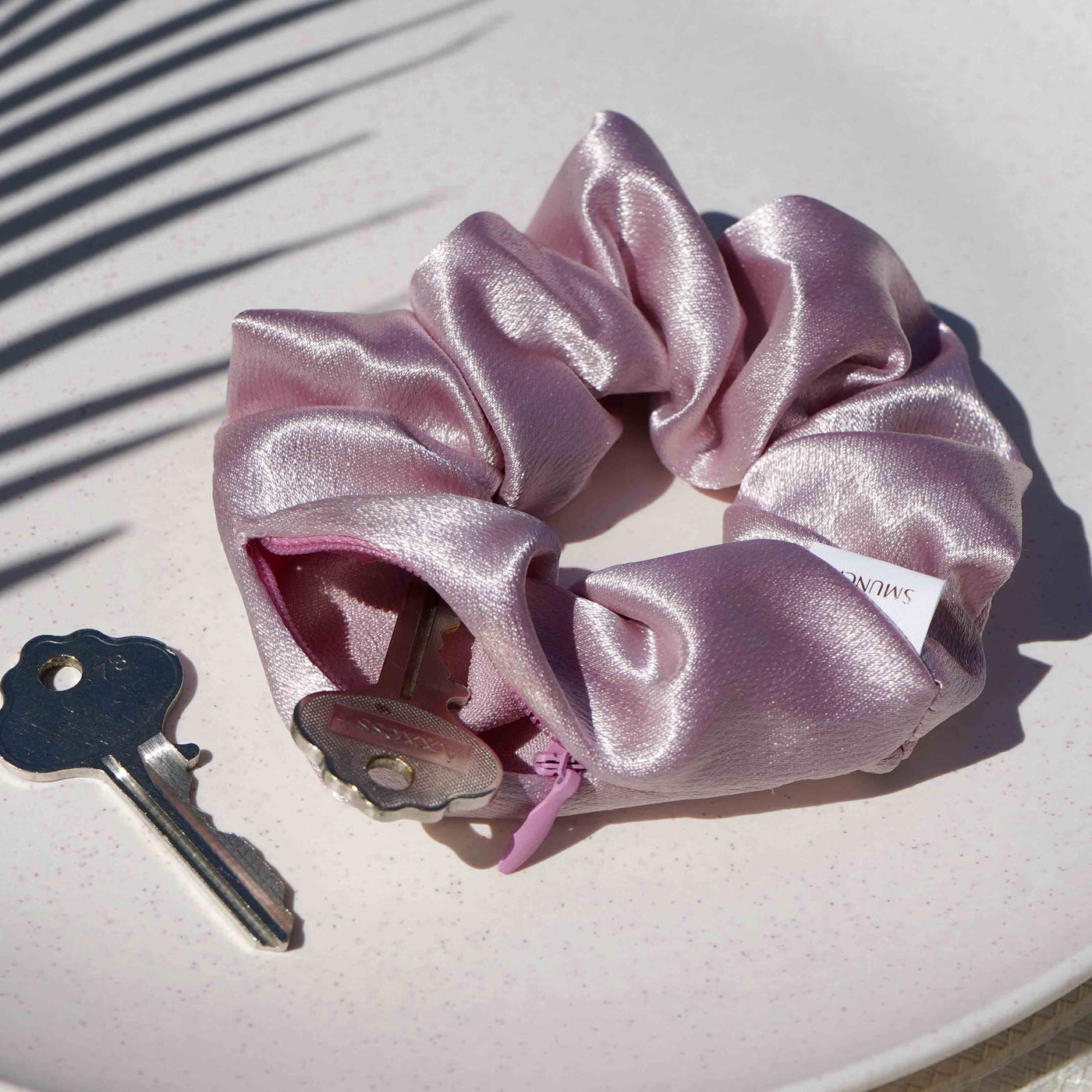 Satin light pink hair scrunchie ponytail holder featuring a hidden zipper pocket for storing valuables (cash, keys, AirPods) and strong elastic for a secure hold. Ideal for workouts, festivals, gifts, and holiday stocking stuffers.