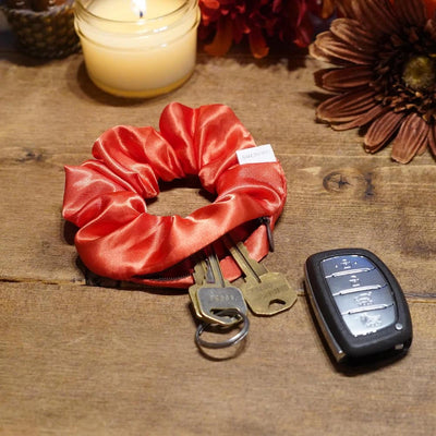 Satin orange fall scrunchie with a hidden zipper pocket for valuables (cash, keys, AirPods), featuring strong elastic for a secure hold, inspired by Halloween, perfect for workouts and festivals.