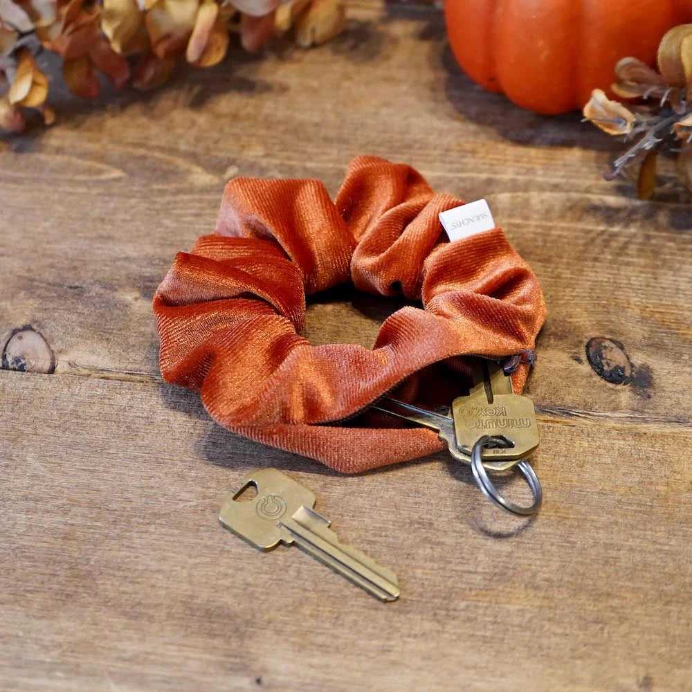 Velvet orange fall scrunchie with hidden zipper pocket for valuables (cash, keys, AirPods), strong elastic for secure hold, inspired by Halloween and fall season, perfect for workouts and festivals.